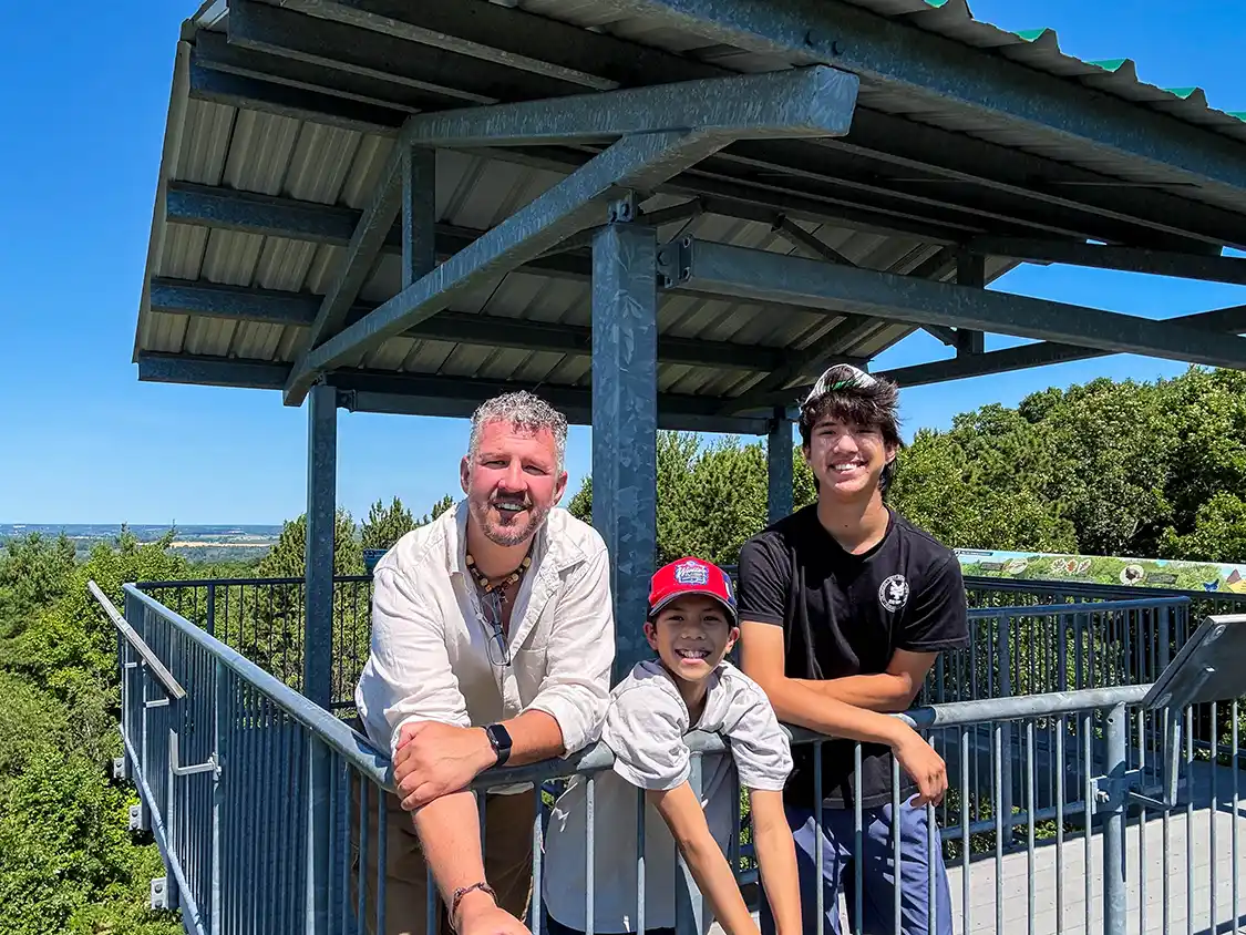 A father and his two sons take a photo at the top of the Sager Conservation Area observation tower