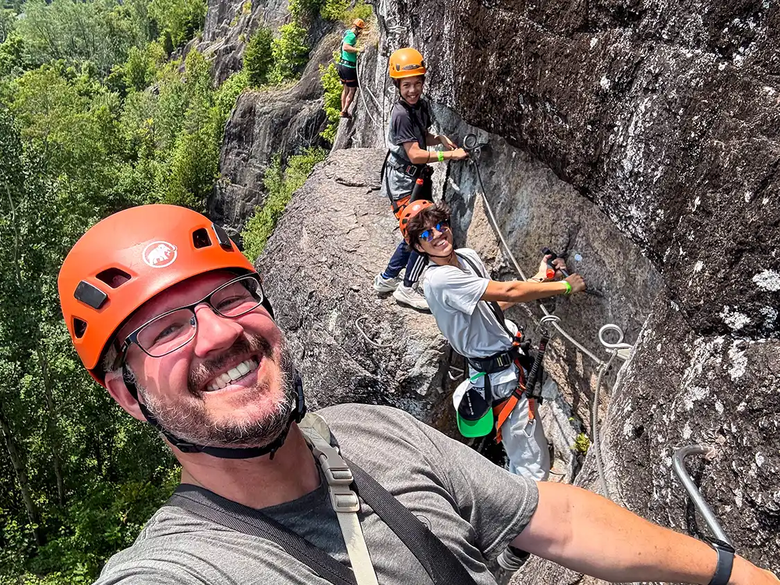 A father and his two sons on a Via Ferrata climbing journey at TyroParc in Quebec