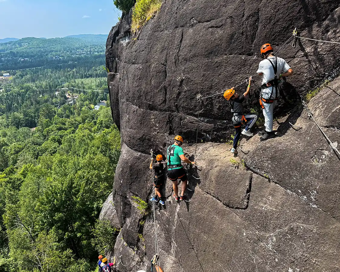 A group of adventurers climb across a mountain on a Via Ferrata in Quebec