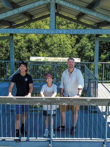 A father and his two sons stand atop an observation tower in Sager Conservation Area while exploring the Bay of Quinte