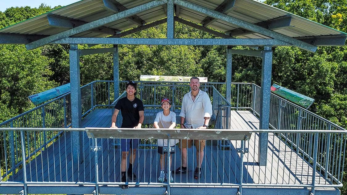 A father and his two sons stand atop an observation tower in Sager Conservation Area while exploring the Bay of Quinte
