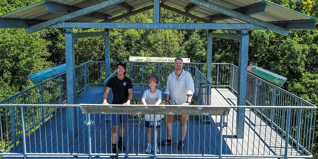 A father and his two sons stand atop an observation tower in Sager Conservation Area while exploring the Bay of Quinte