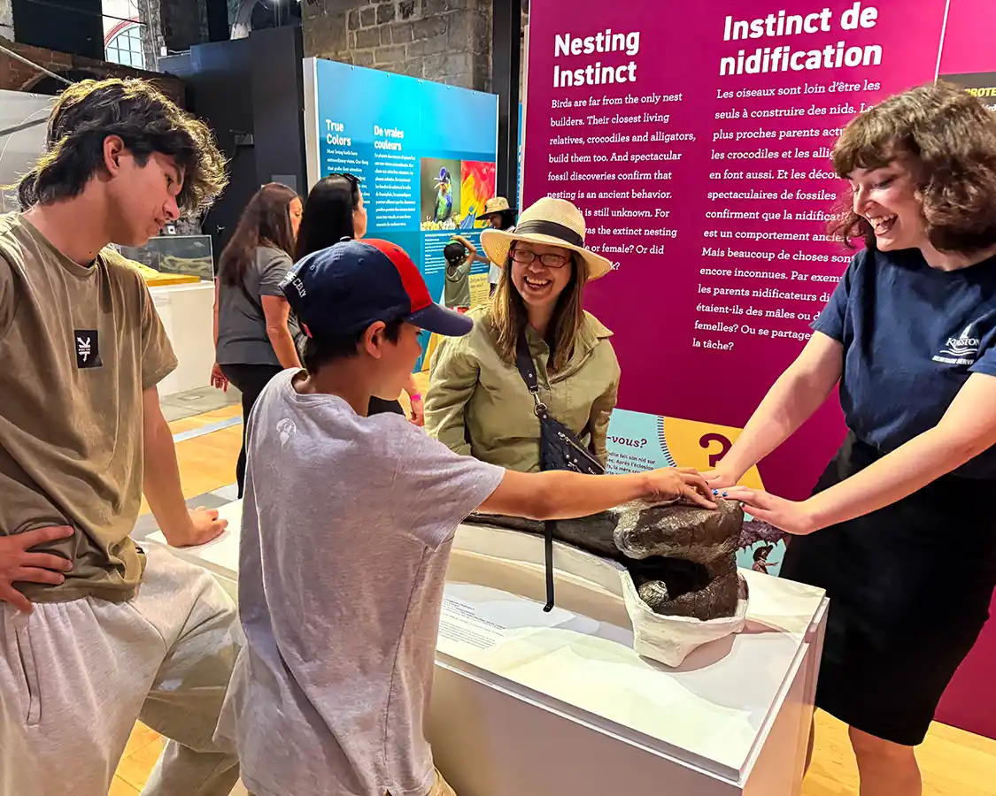 A family smiles while touching a dinosaur bone at the Kingston Pumphouse Museum