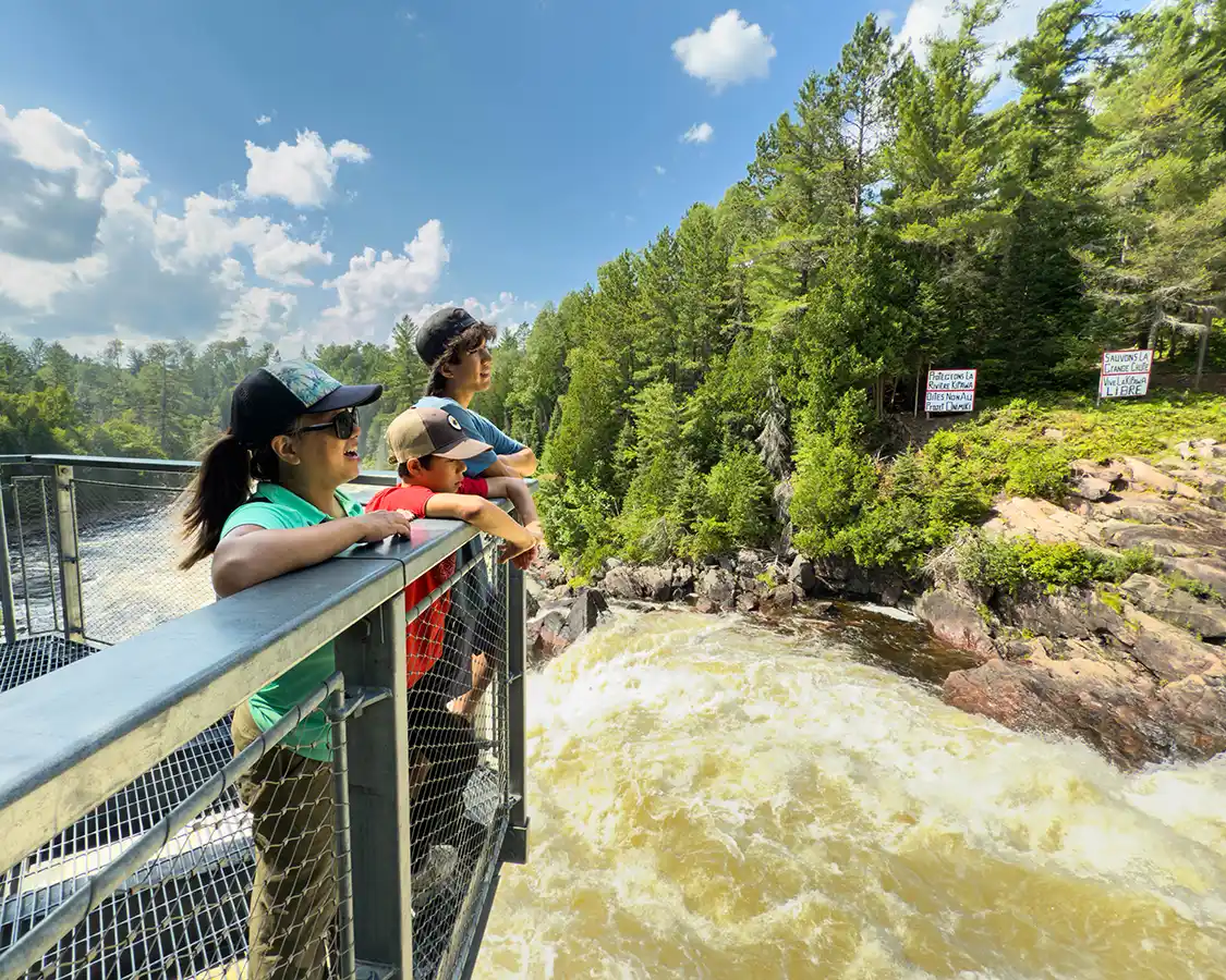 A woman and her two children look out at Grand Chute waterfall in Opemican National Park, Quebec