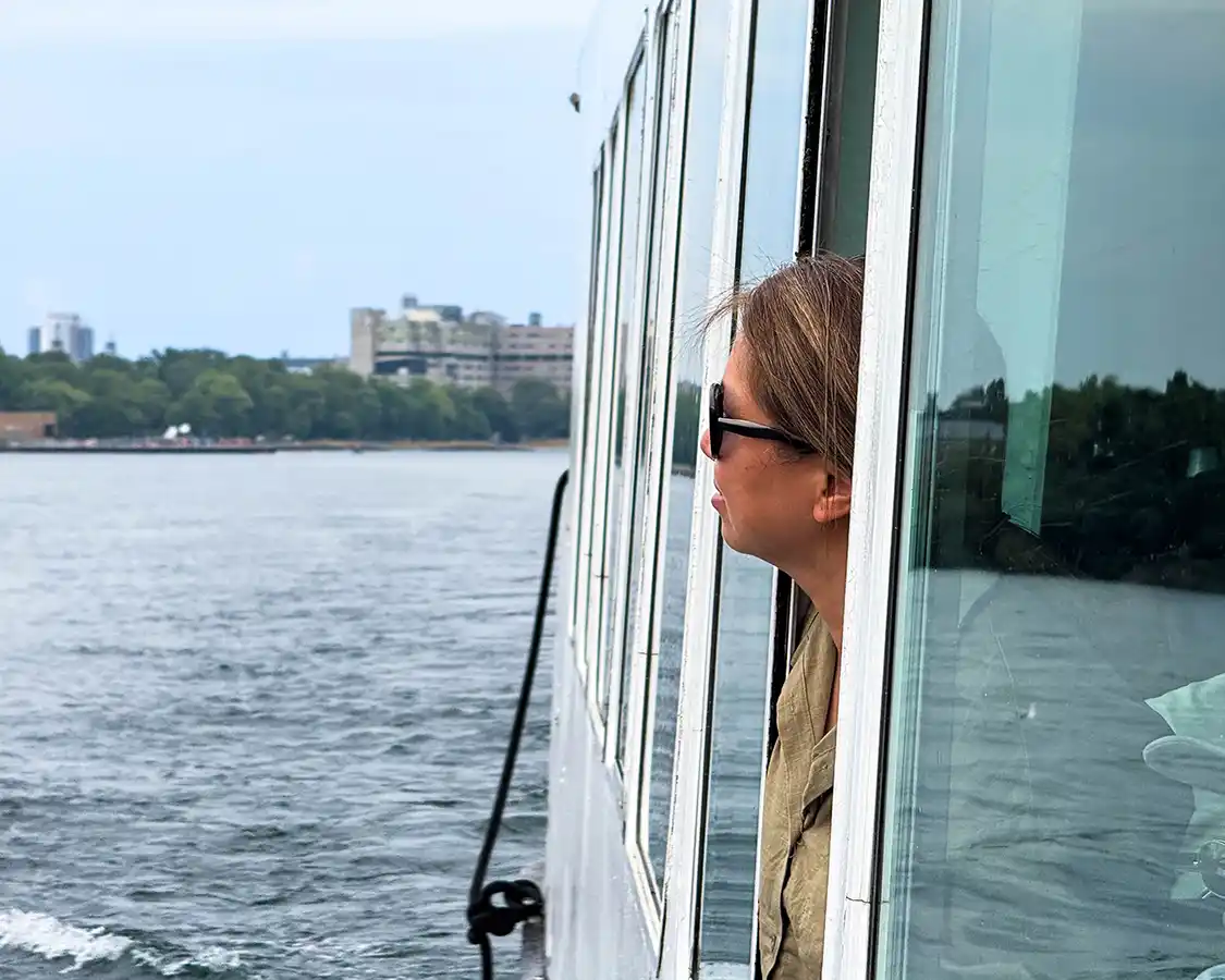 A woman looks out the window of a boat while taking a 1000 Islands Shipwreck Cruise in Kingston, Ontario