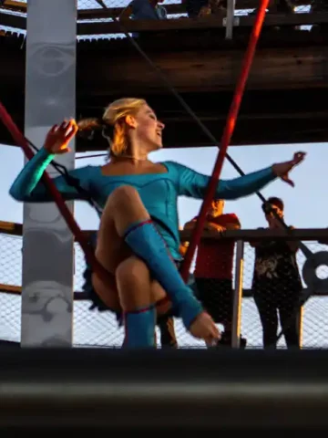A female acrobat performs on an aerial silk in an open-air observatory tower during summer in Mont Tremblant