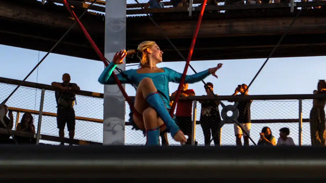 A female acrobat performs on an aerial silk in an open-air observatory tower during summer in Mont Tremblant