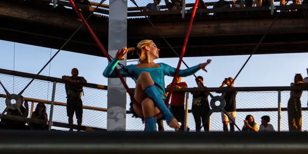 A female acrobat performs on an aerial silk in an open-air observatory tower during summer in Mont Tremblant
