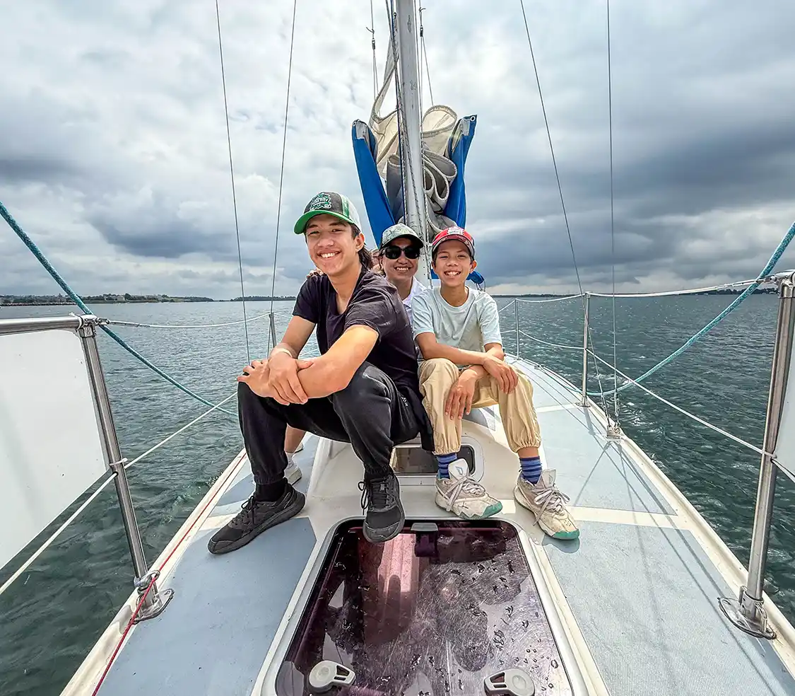 A family sits on top of a sailboat while sailing Lake Ontario with Ahoy Rentals in Kingston