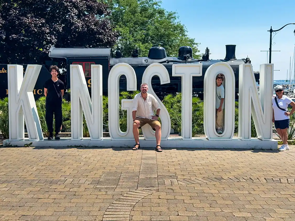 Wandering Wagars family pose dramatically on the Visit Kingston Sign on the Kingston Waterfront