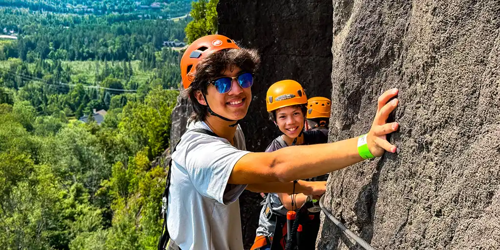 What is Via Ferrata? Two boys climb across the face of a cliff in Quebec