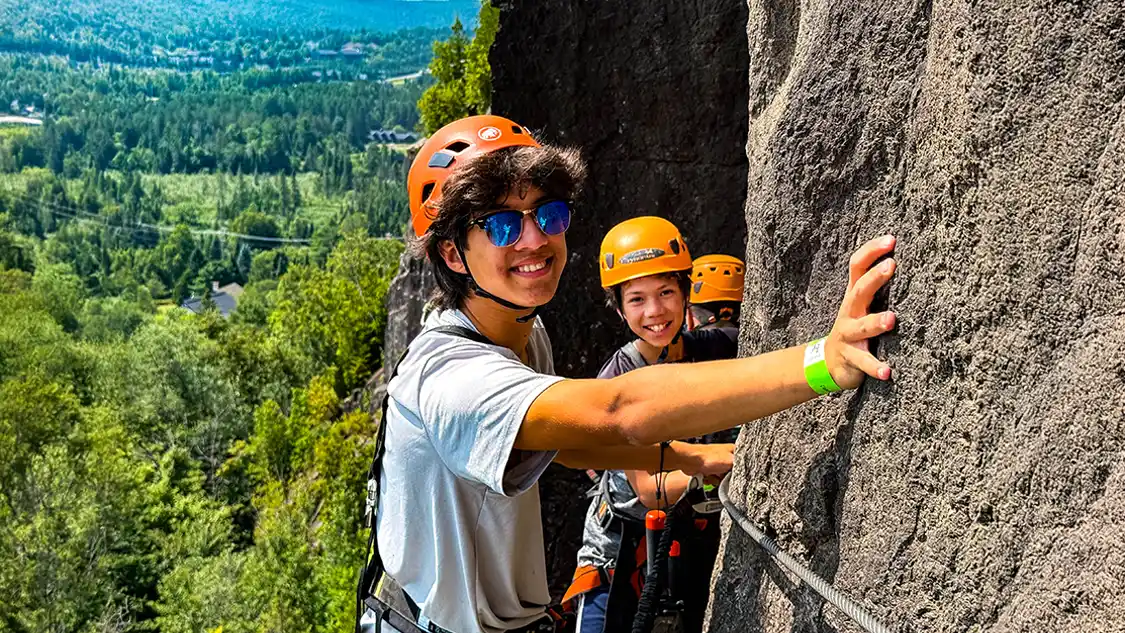 What is Via Ferrata? Two boys climb across the face of a cliff in Quebec