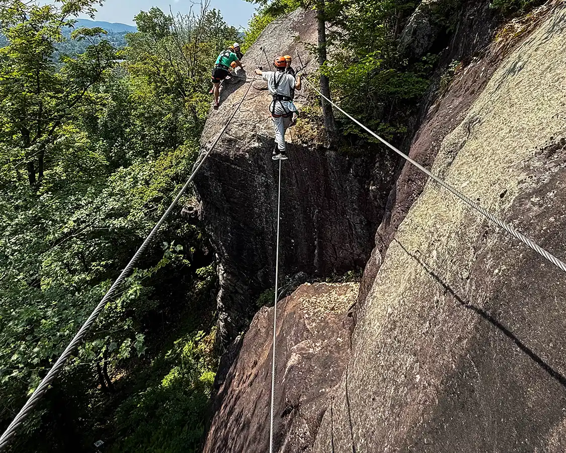 A teenager walks across a cable line on a Via Ferrata in Quebec