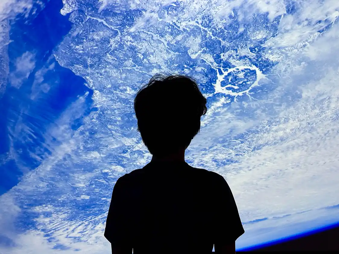 A boy looks out over a planet from a space station at ASTROLab in Parc National Mont-Megantic