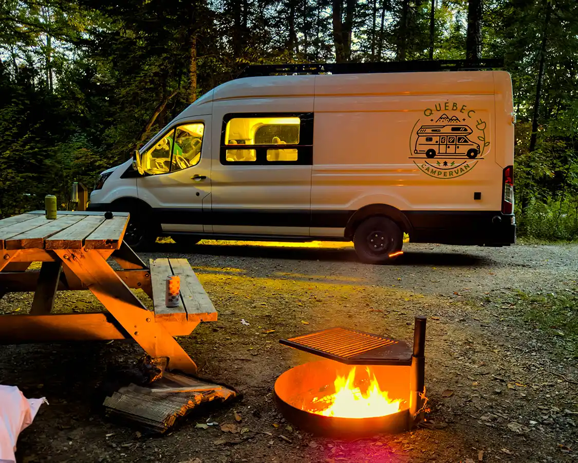 A campervan in front of a fire pit at night in the Franceville campground in Mont-Megantic National Park