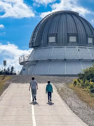 Two boys walk up a road toward a mountain-top observatory in Mont-Megantic National Park