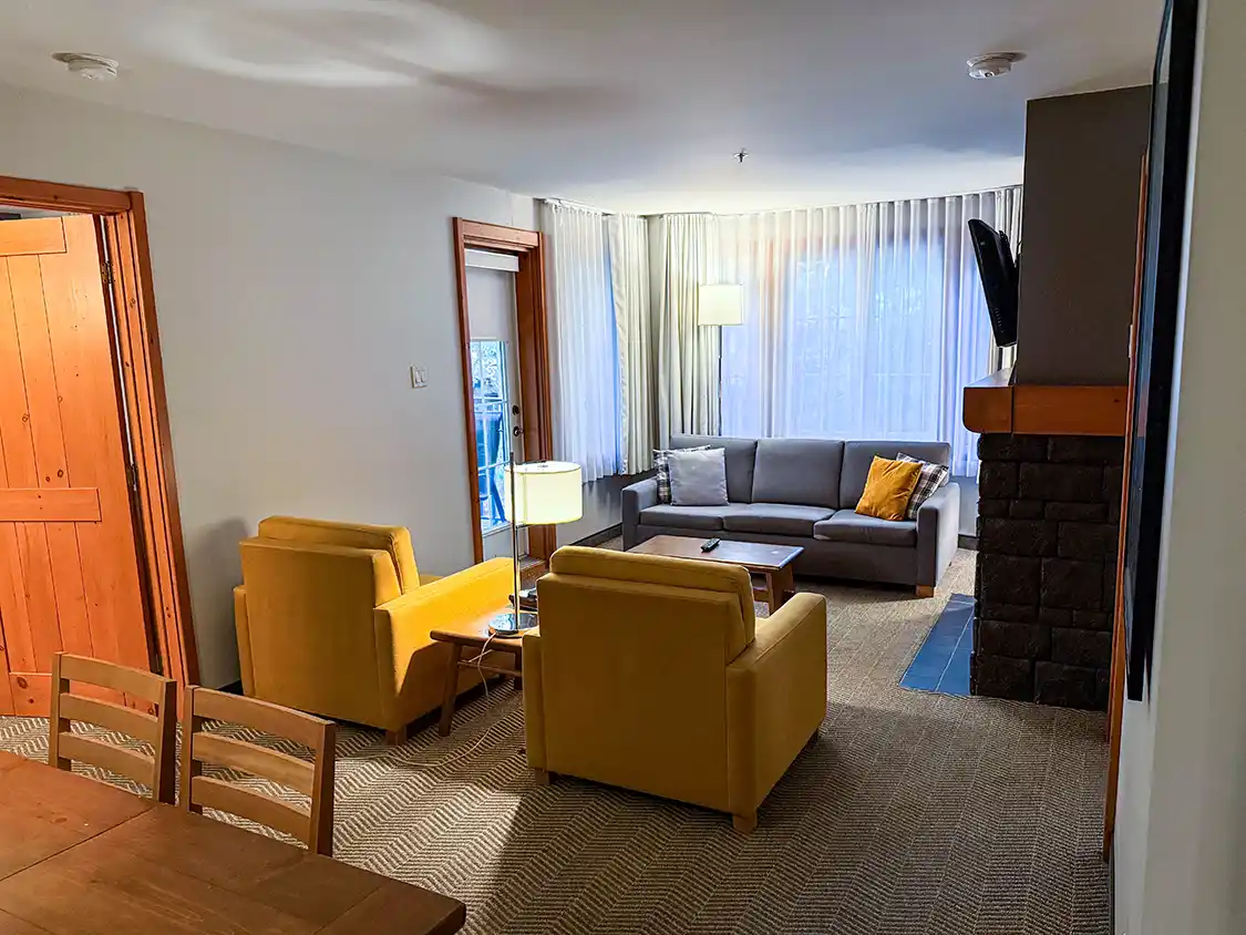 A cozy living room at a ski resort hotel room in Tremblant, Quebec. A fireplace, chairs and a couch by a large window