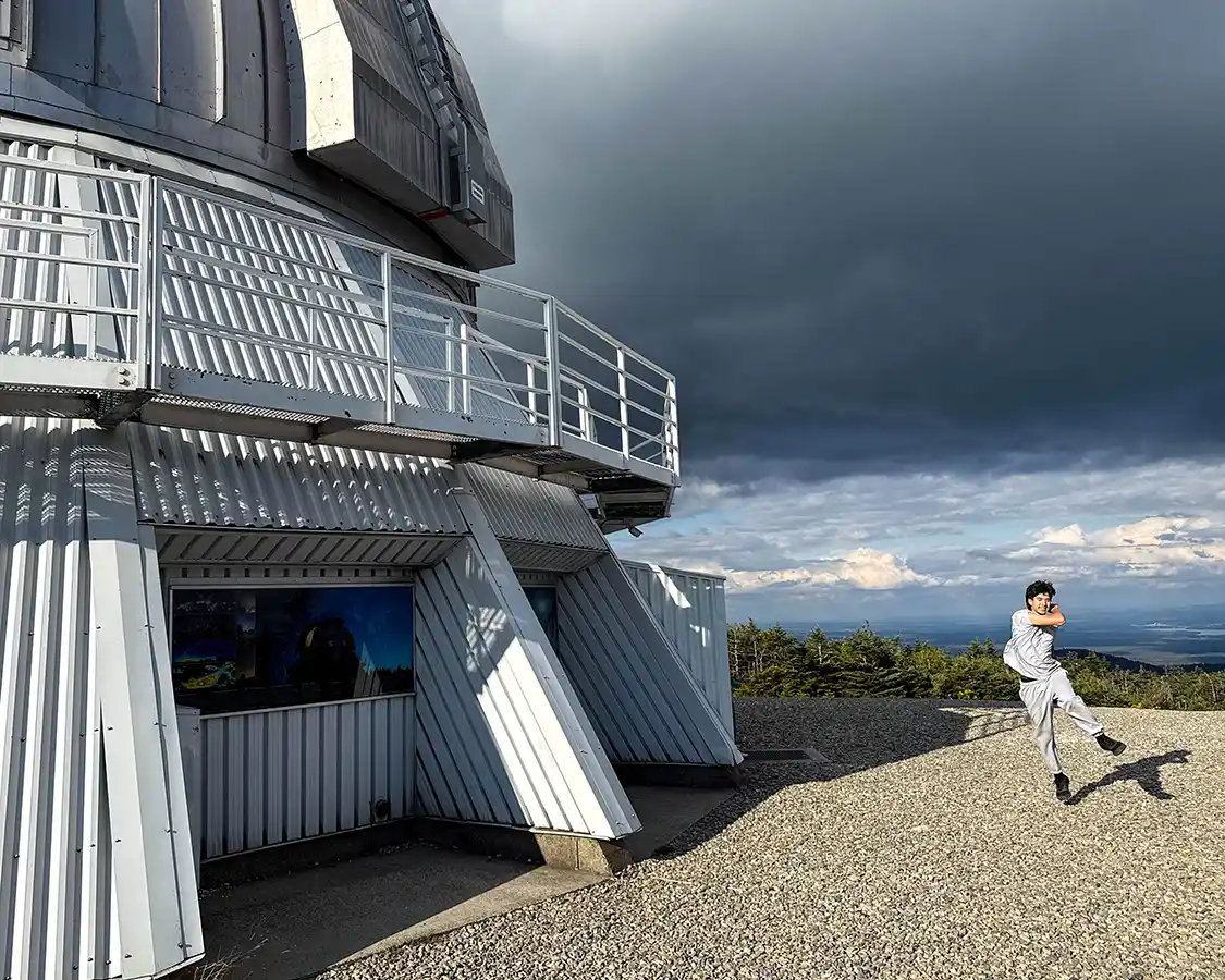 A teenager leaps out of the doors of the Observatory in Parc National Mont-Megantic