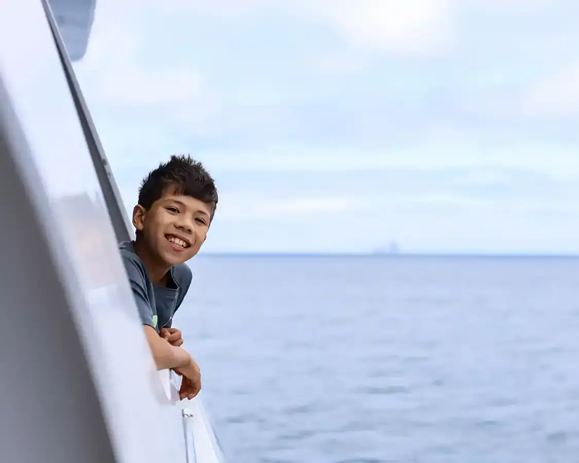 A young boy smiles while sticking his head out of a cruiseship cabin in the Galapagos Islands