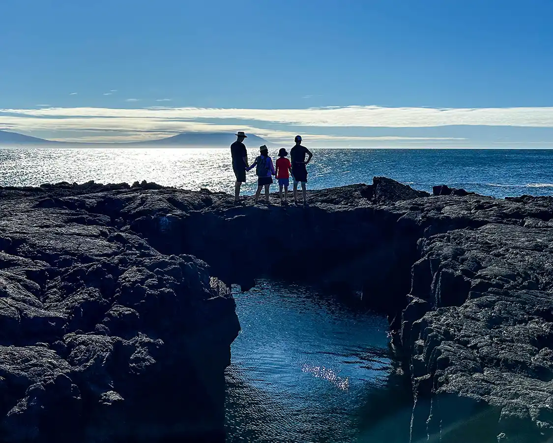 Wandering Wagars family stand on a natural stone bridge in the Galapagos Islands