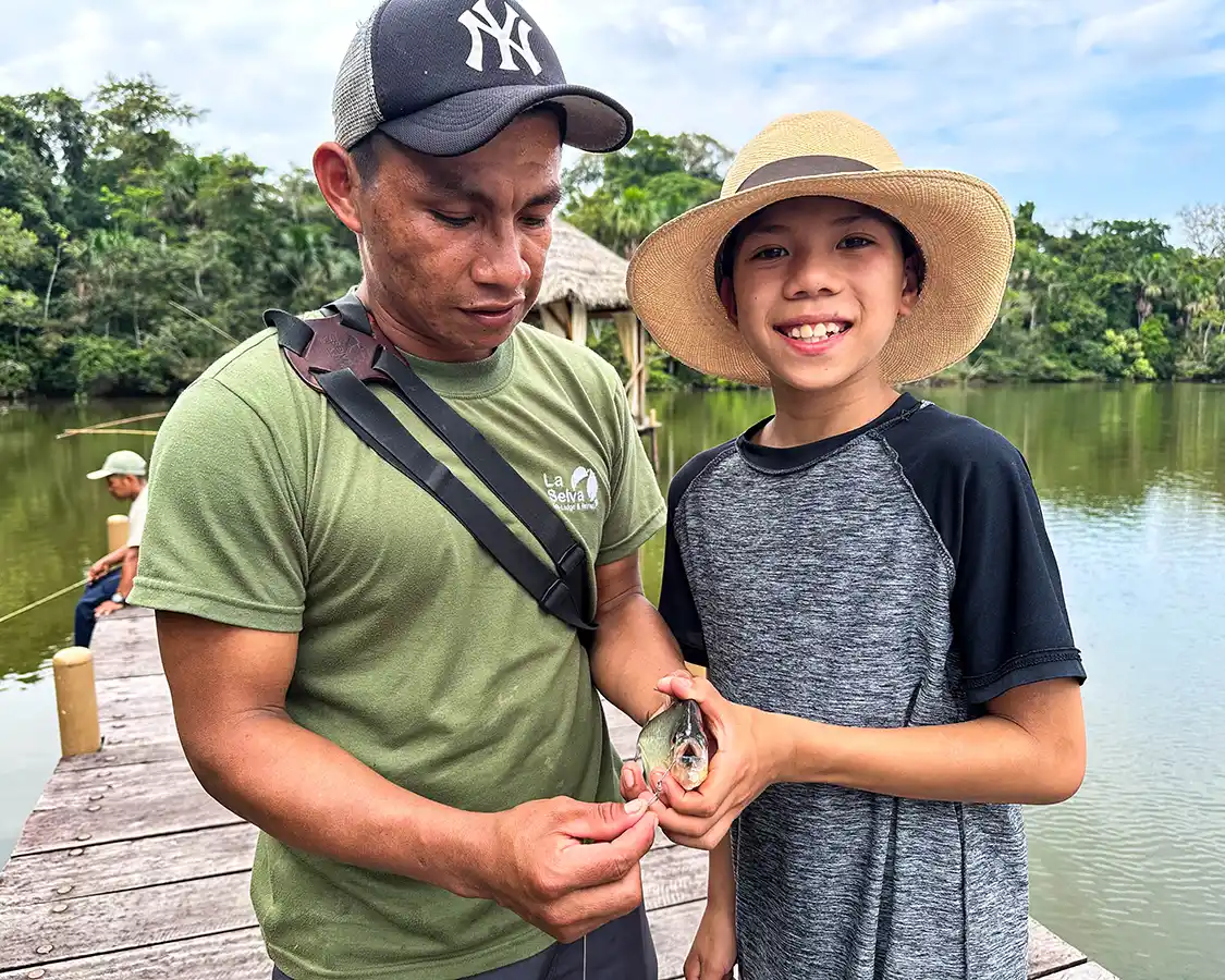 A boy an an Amazon guide pose with a pirhana that they caught while fishing
