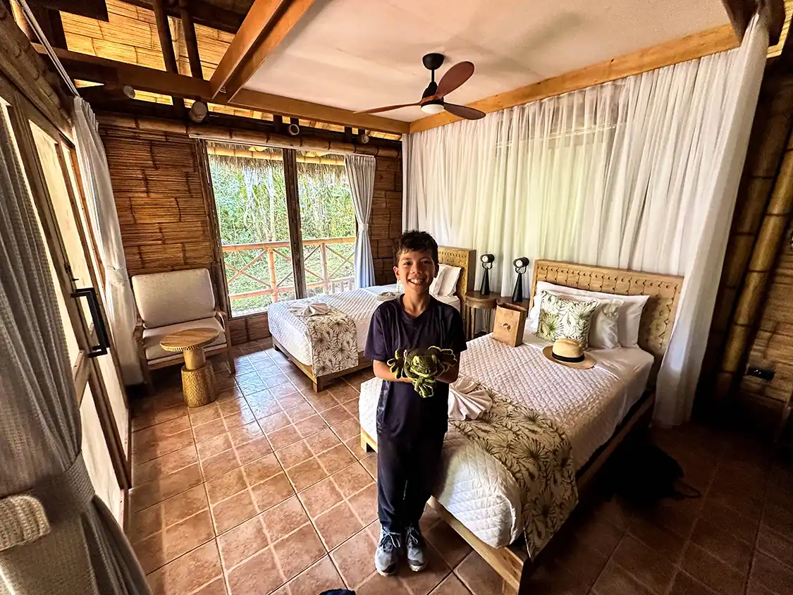 A boy poses with a stuffed frog inside a junge lodge in the Ecuadorian Amazon