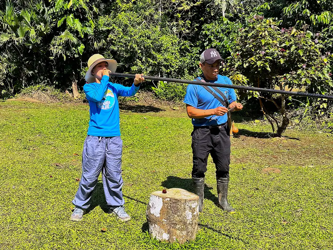 A boy shoots a blow dart at a target in a Pilche village in Ecuador