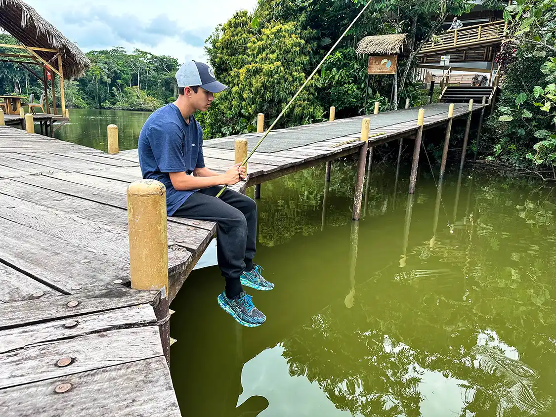 A boy sits glumly while trying to catch pirhana in the Amazon rainforest