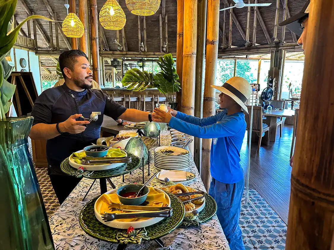 A chef serves food to a boy at La Selva Eco Lodge