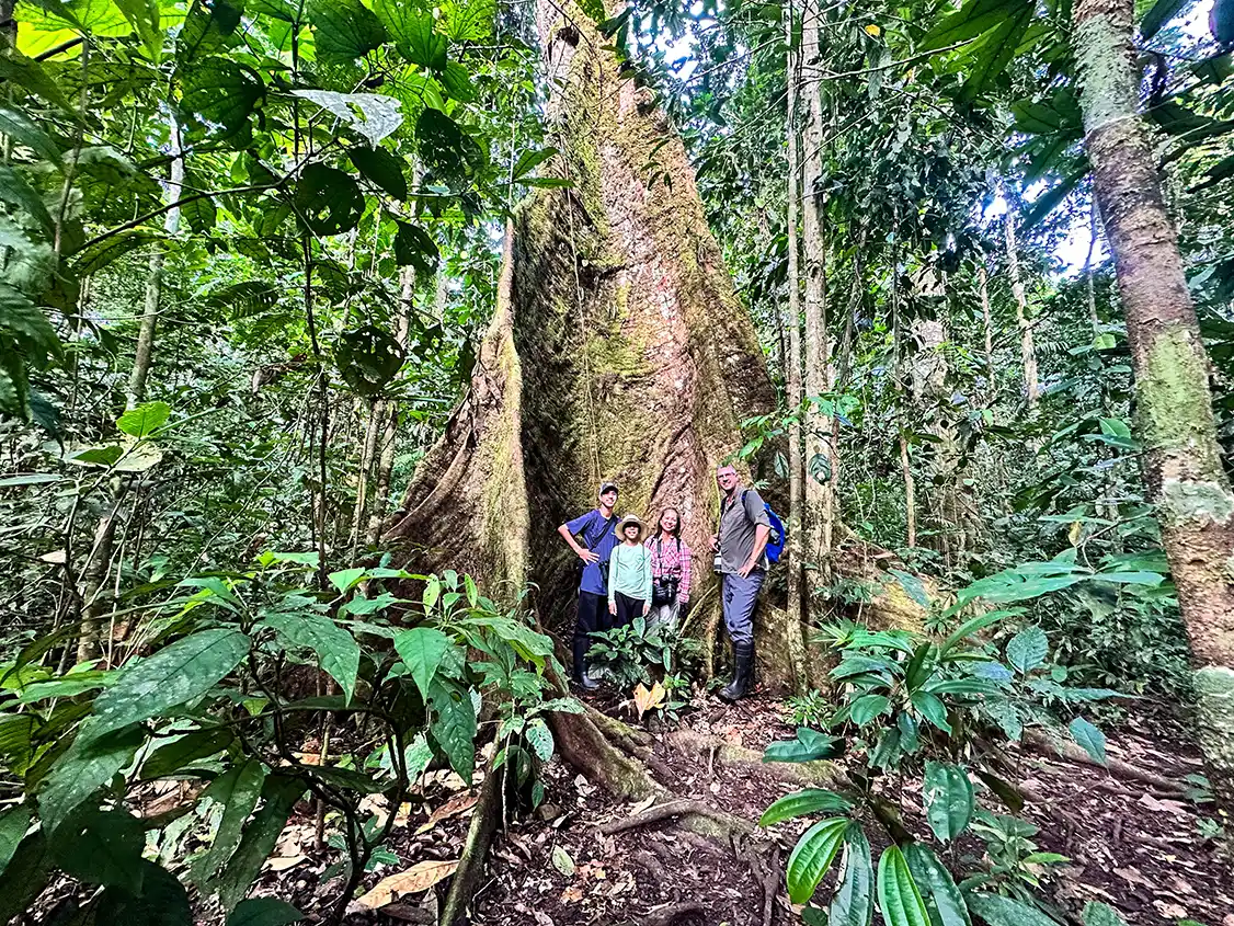 A family poses beside an endangered mahogany tree in the Amazon Rainforest
