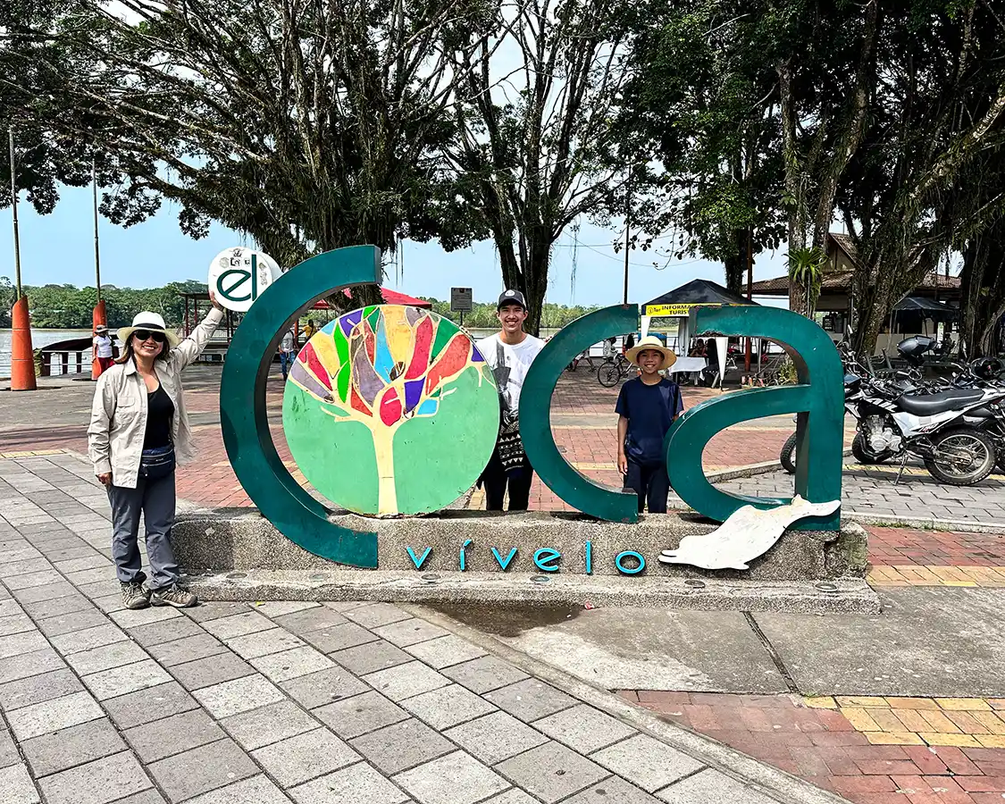 A family poses in front of the Vivelo Coca sign in Coca Ecuador