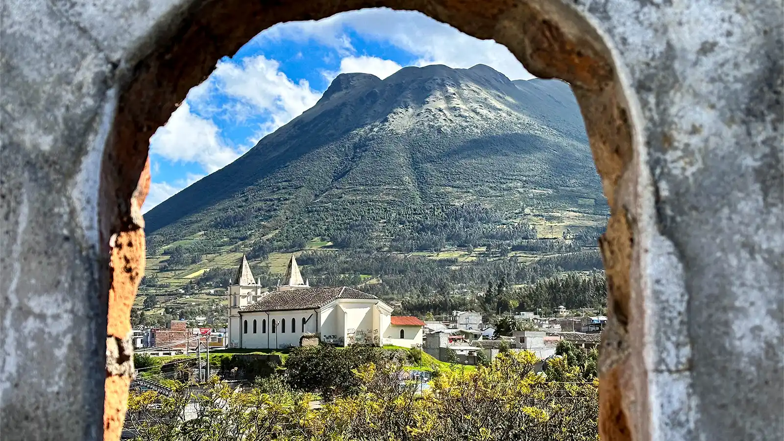 A view of accommodations in Otavalo, Ecuador from a stone archway