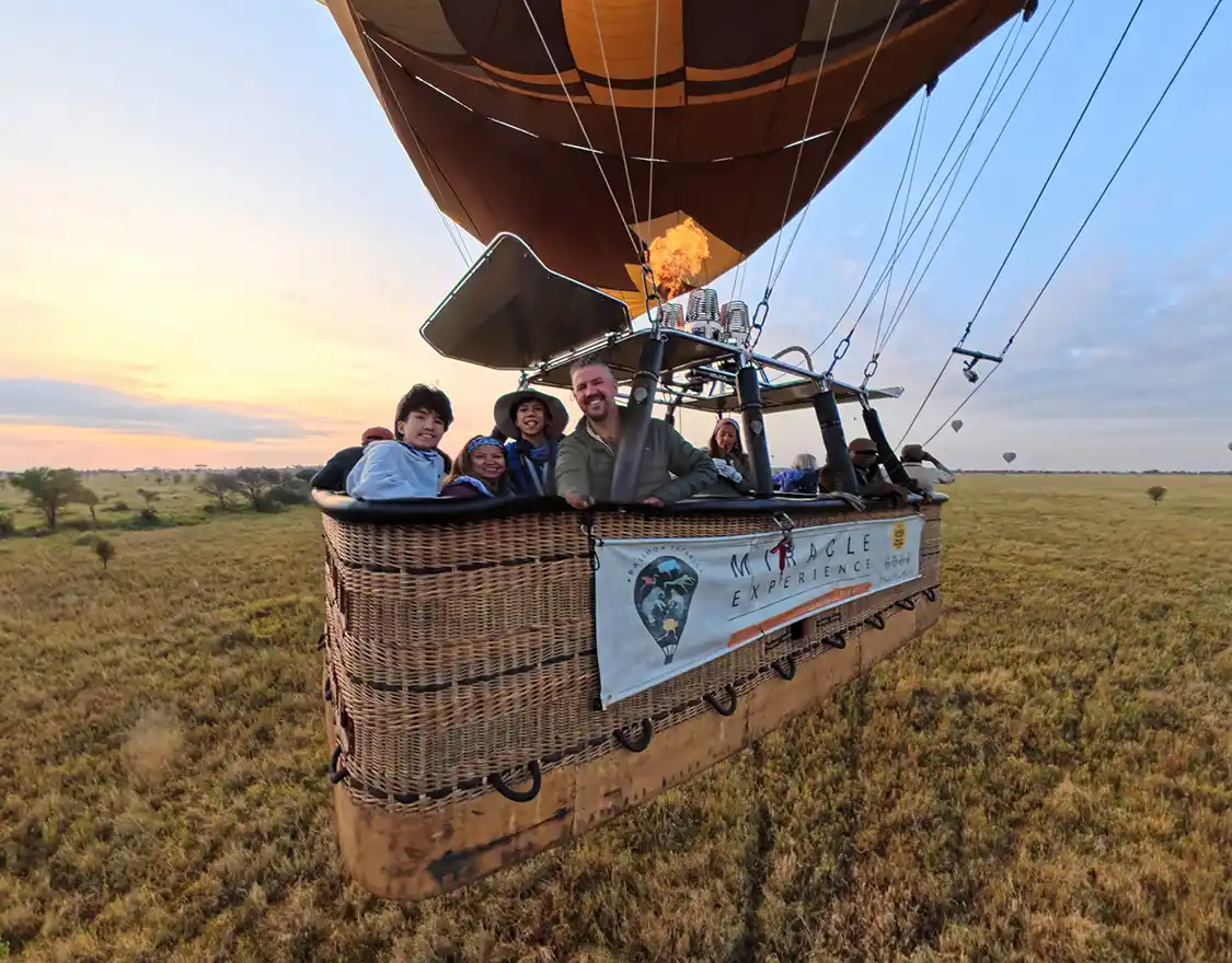 A family in a sunrise hot air balloon over Serengeti National Park Tanzania