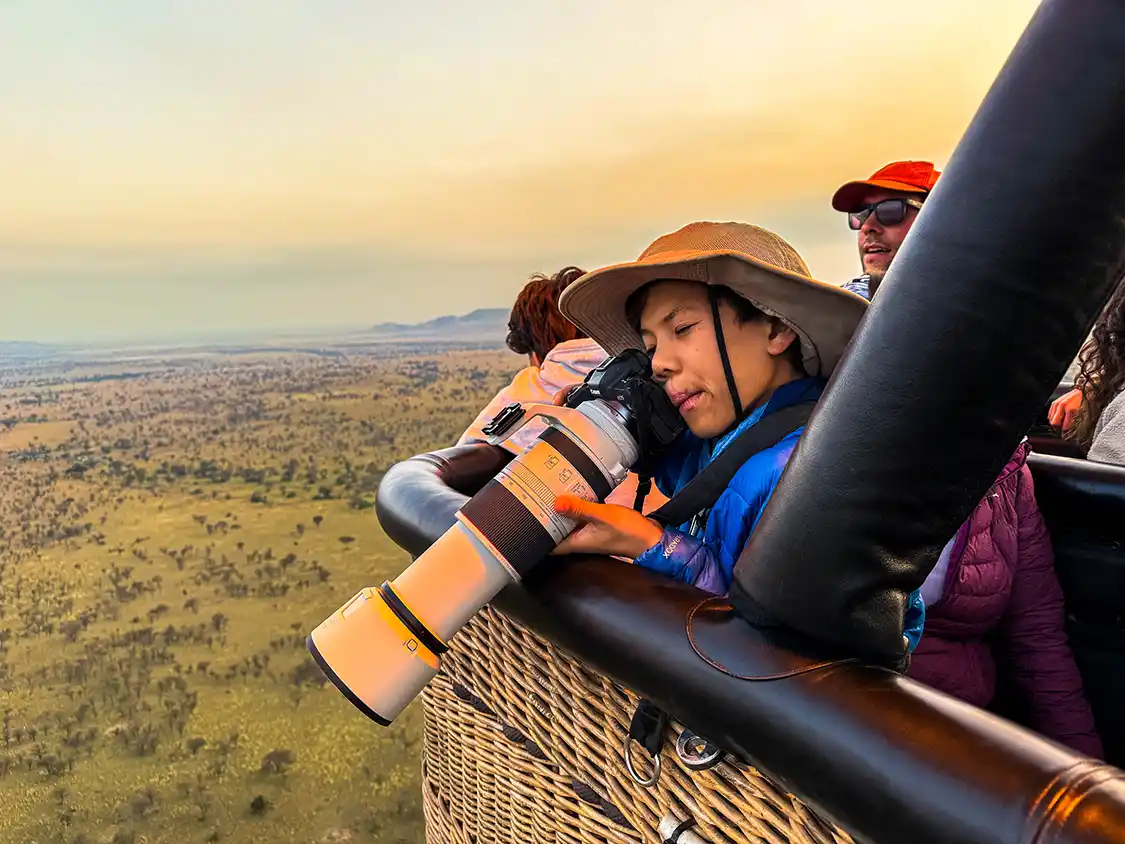 A young boy takes a photograph from a hot air balloon in Serengeti National Park