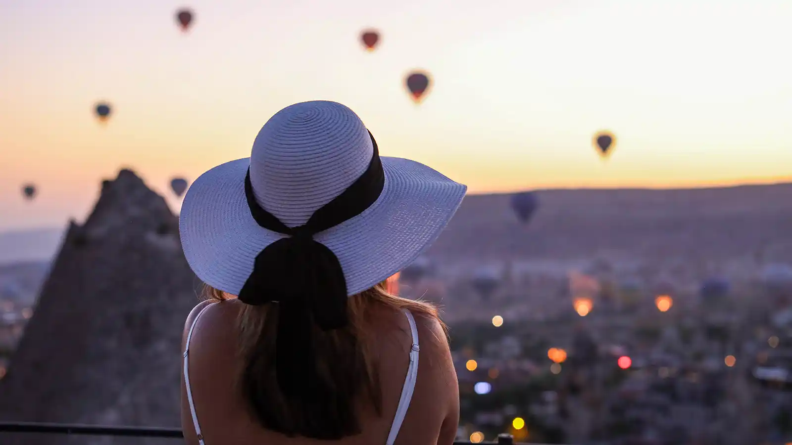 Woman standing on a terrace watching hot air balloons over Cappadocia during family travel in Turkey
