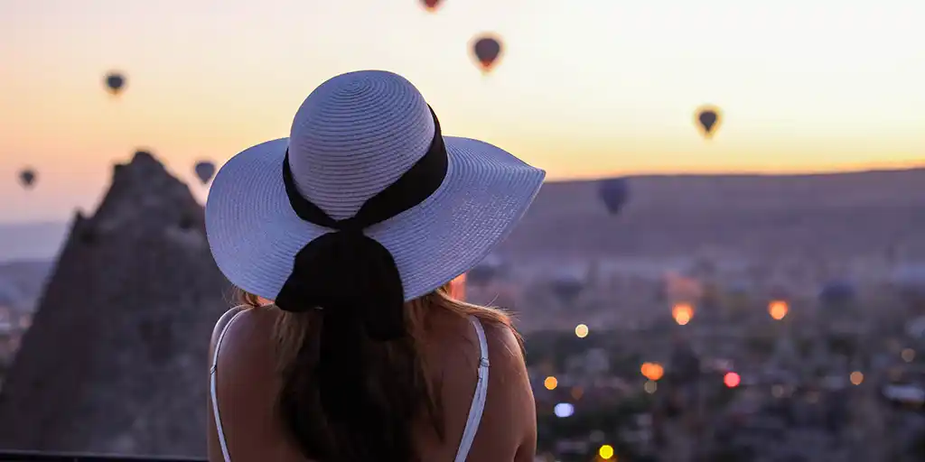 Woman standing on a terrace watching hot air balloons over Cappadocia during family travel in Turkey