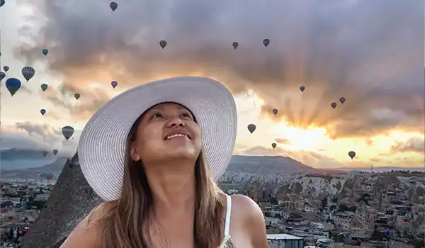 Woman with a white hat looking at hot air balloons in Cappadocia, Turkey International Family Travel