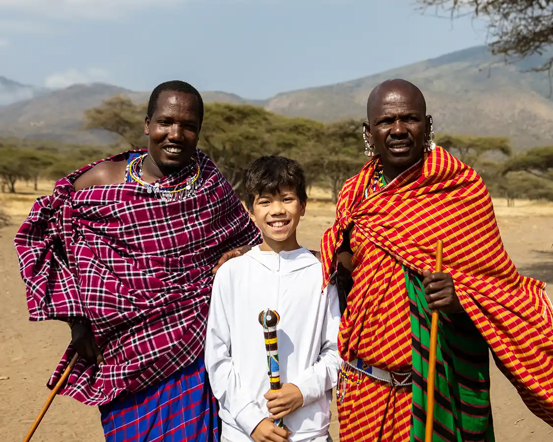 Boy standing with two Masai men in Ngorongoro Conservation Area Tanzania