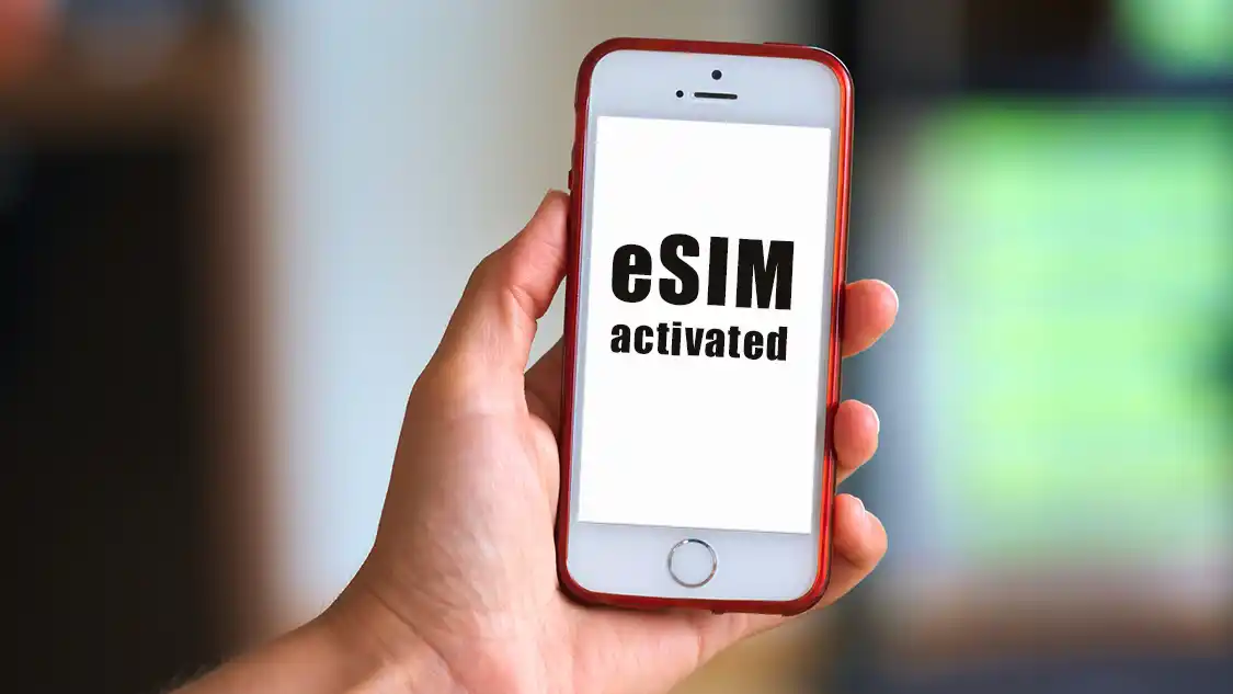 Hand holding a phone with a message showing eSIM activated