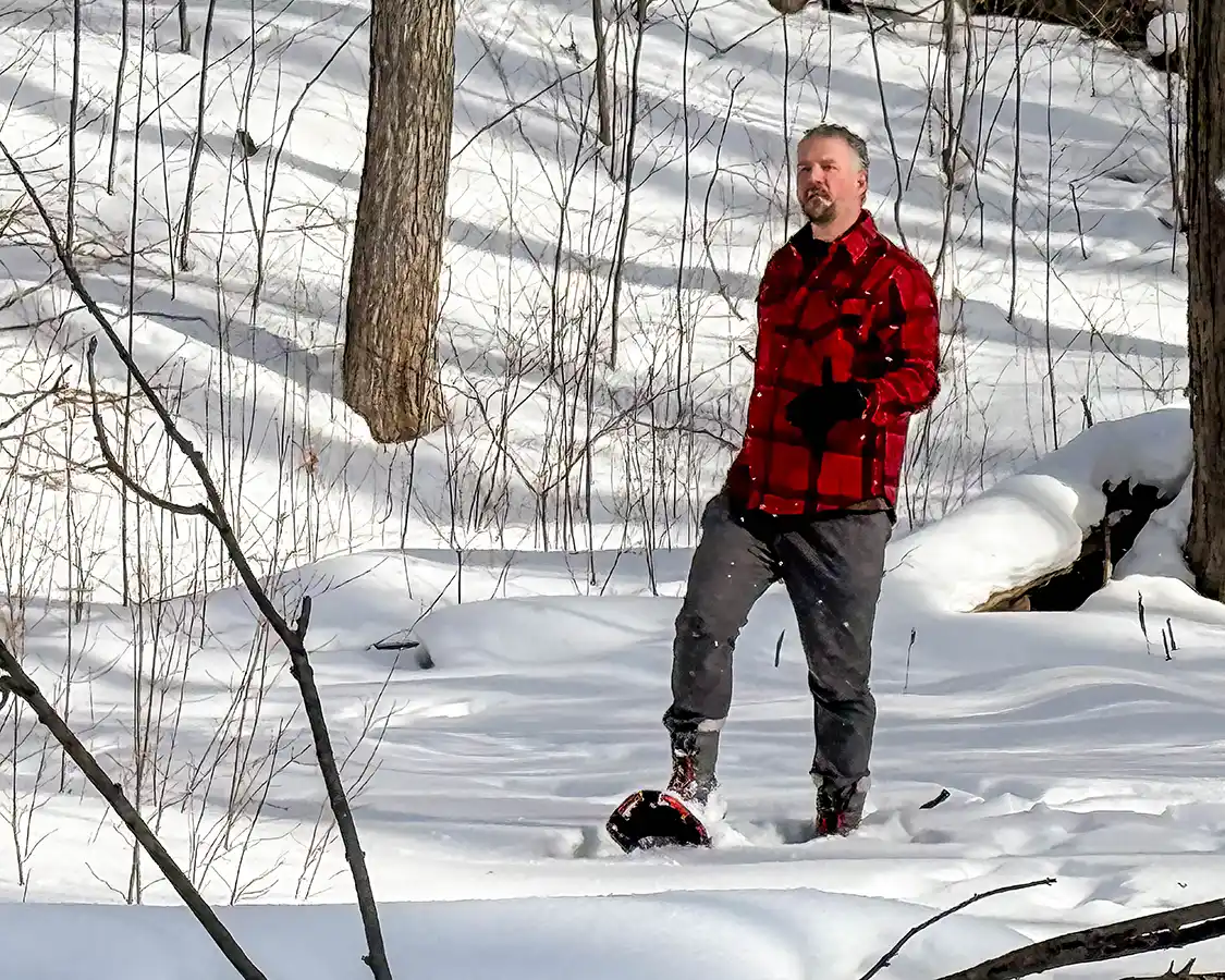 Man in a red coat snowshoeing the backcountry trails in Heart Lake Conservation Area