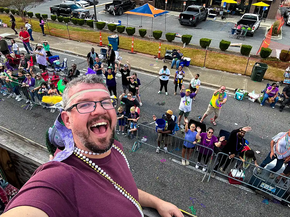 Man smiling whil wearing a mask backwards on a Mardi Gras Float in Lafayette Louisiana