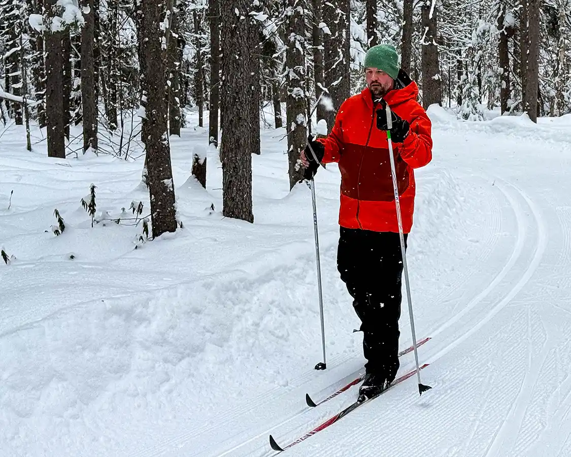 A man wearing an orange jacket and green toque cross-country skiing at Kamview Nordic Center in Thunder Bay