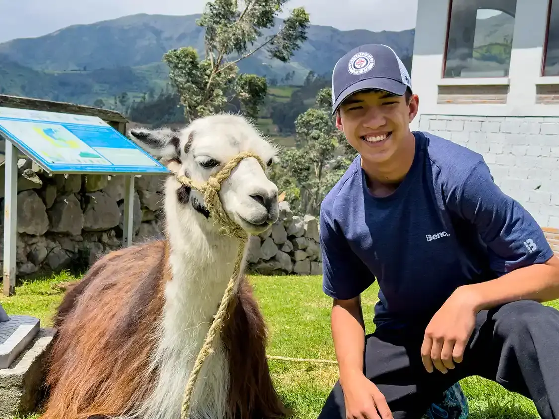 A teenage boy talking with a llama near Quito Ecuador