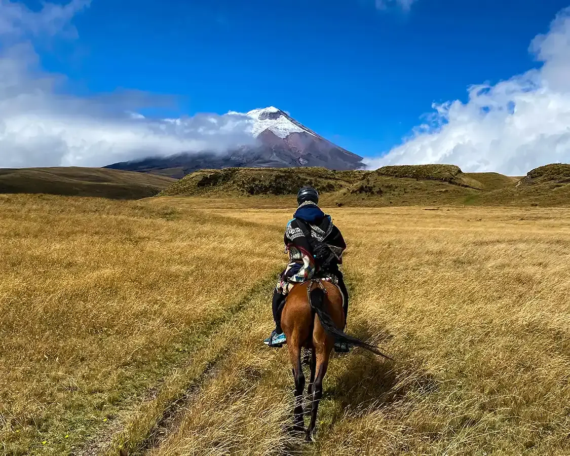 A teenager rides a horse toward Cotopaxi Volcano in Ecuador