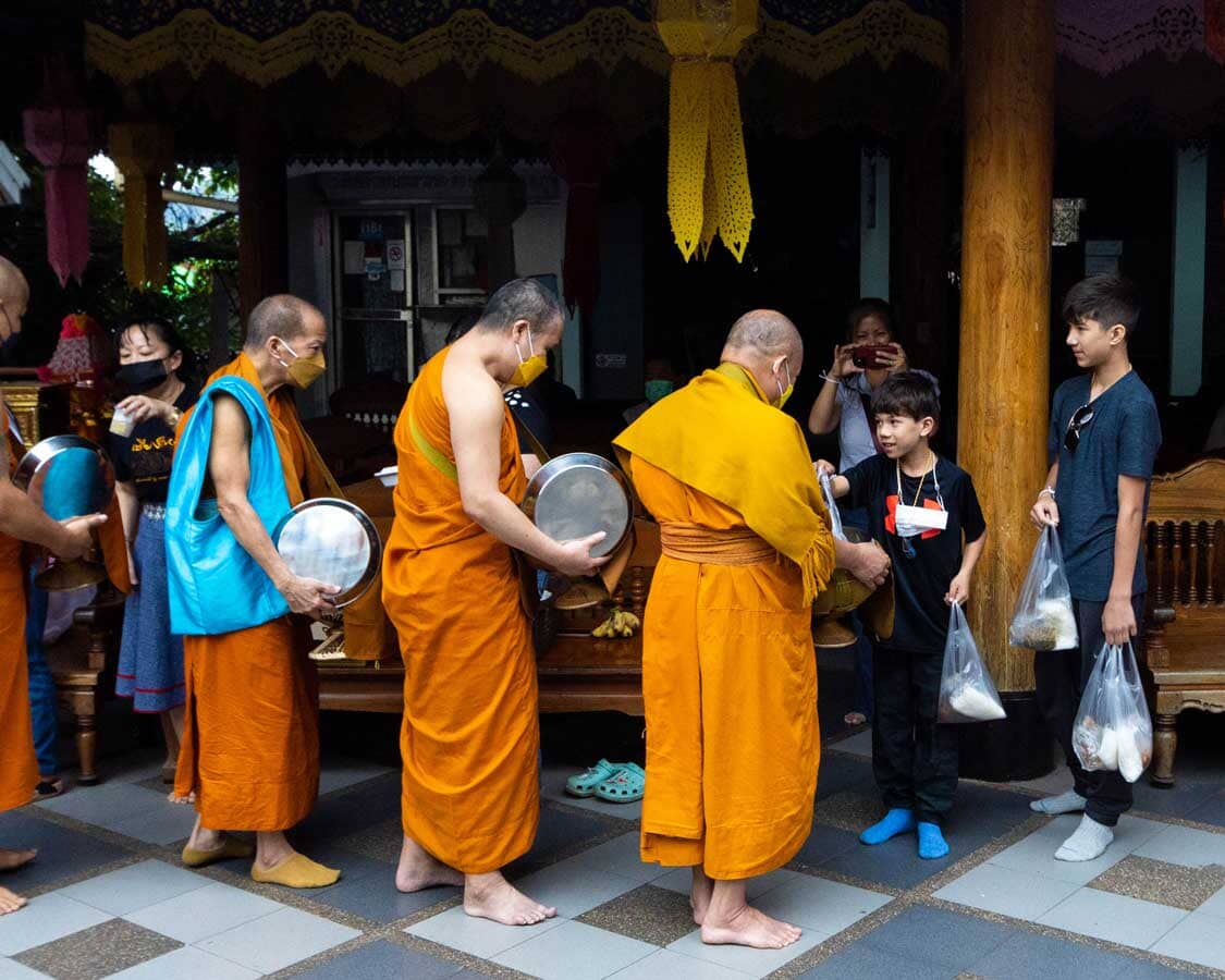 Children giving ohms to Buddhist monks in Thailand