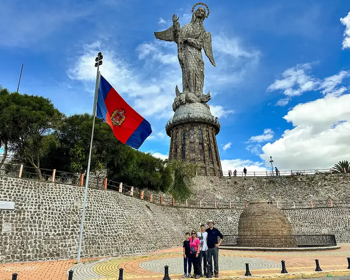 Family posing in front of the Virgin of El Panecillo statue in Quito