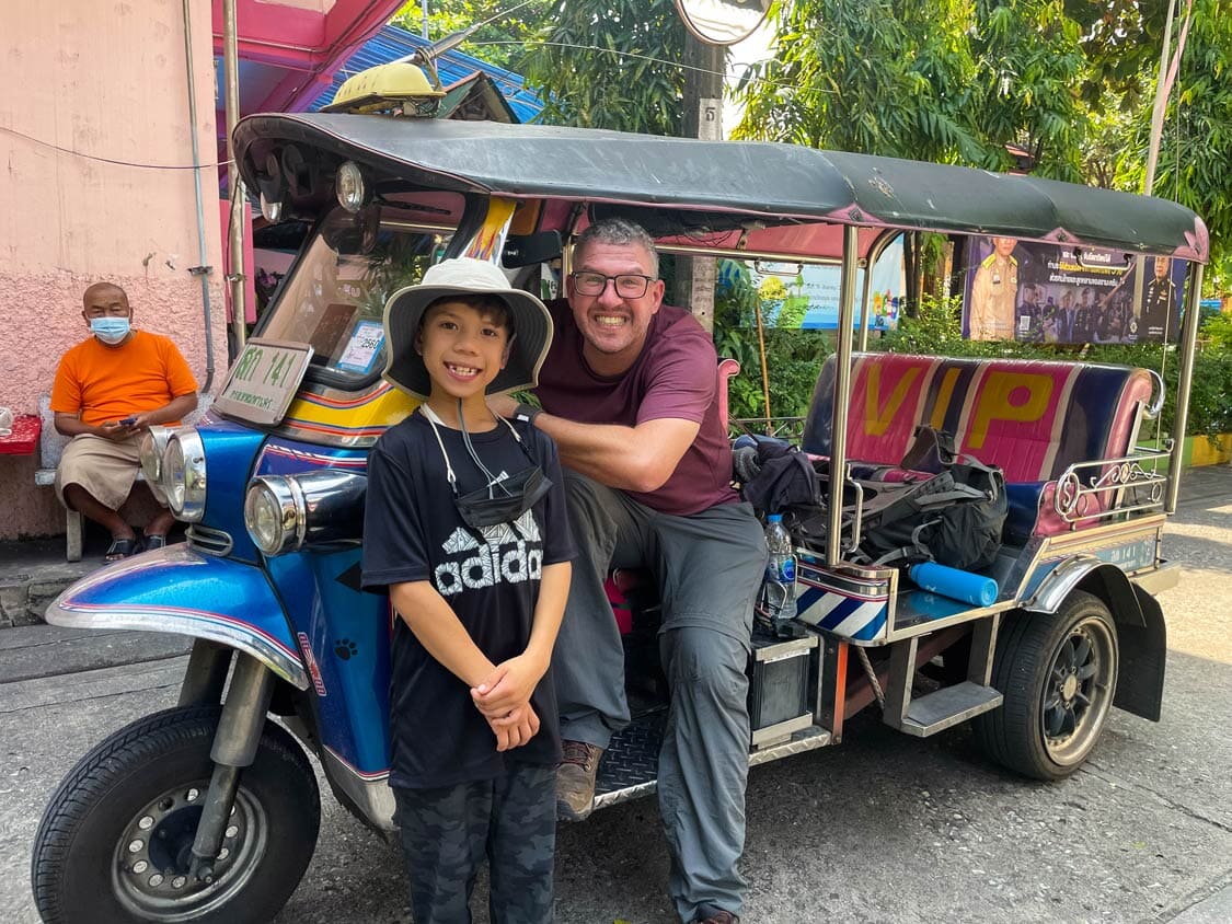 A father and son pose inside a tuk tuk in Bangkok