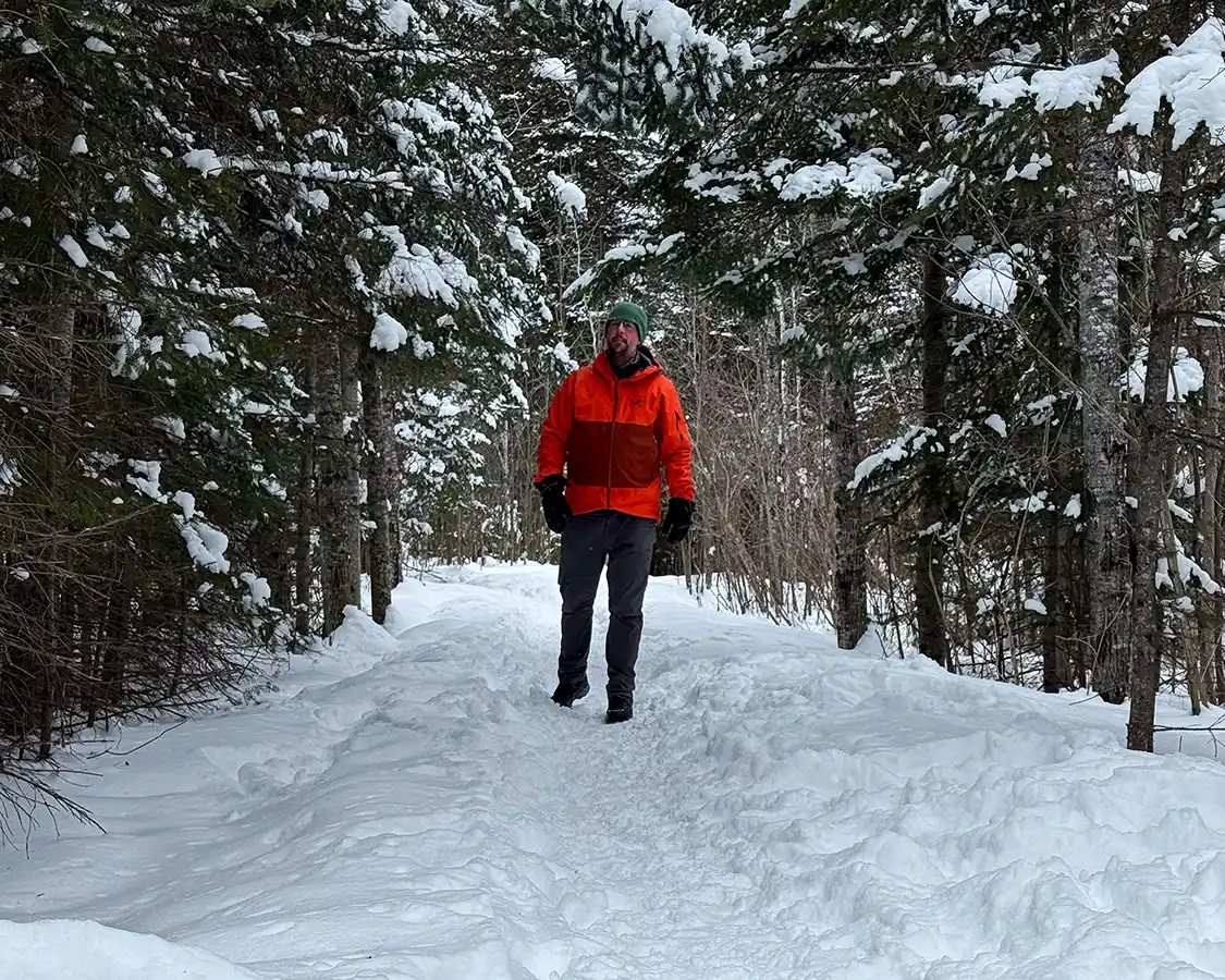 Man in an orange jacket winter hiking in Kakabeka Provincial Park