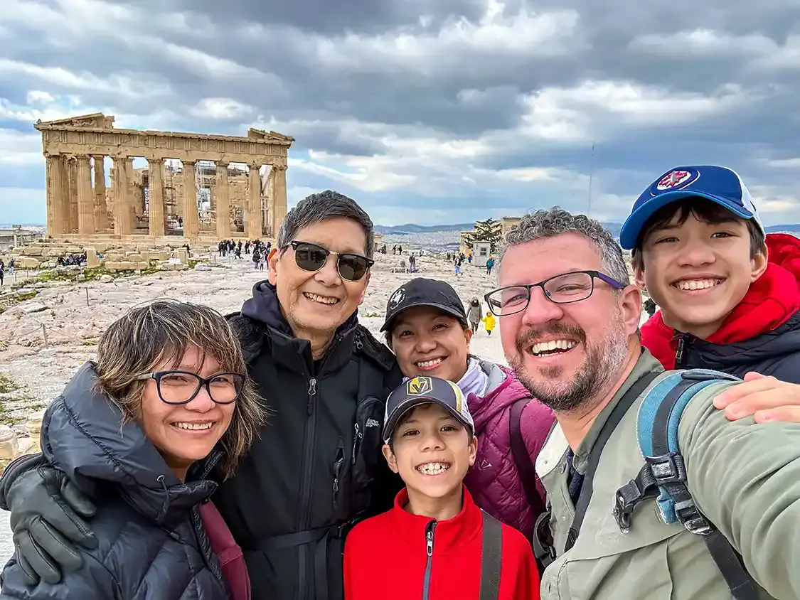 Three generations of a family stand together at the Acropolis in Athens Greece