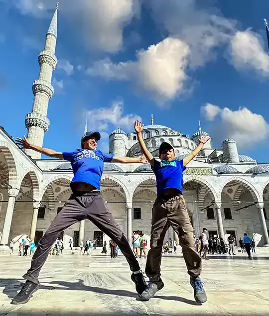 Two boys jump for joy in front of the Blue Mosque in Istanbul Turkey Family Travel Tips